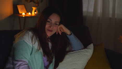 Smiling-Woman-Sitting-On-Sofa-At-Home-At-Night-Streaming-Or-Watching-Movie-Or-Show-On-Laptop